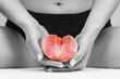 © _KUBE_ - A woman holds half a grapefruit between her legs with two hands. A black and white picture with a colored grapefruit. Close up. The concept of gynaecology and women's health