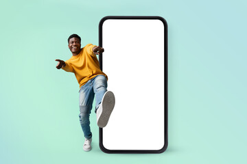 Poster - Hey you, check this website. Excited black man standing near huge smartphone with blank screen, mock up
