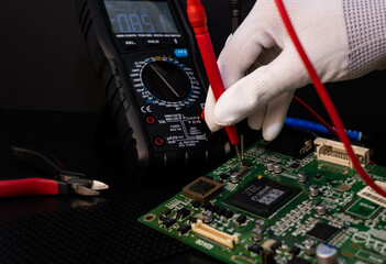 Man checking computer motherboard with a multimeter.