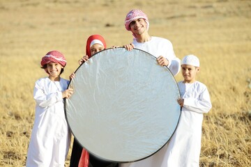 Wall Mural - Arabic family in nature holding copy space banner