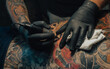 Hands of a tattoo artist holding a machine while working