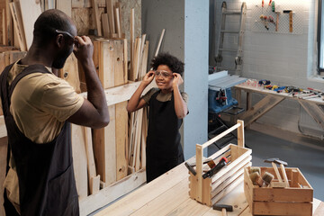 High angle portrait of black father and son working together in garage workshop, copy space