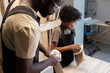 © pressmaster - Portrait of black father and son sanding wood in carpentry workshop together, copy space