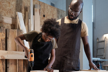 Wall Mural - Portrait of cute African-American boy with father in workshop building wooden furniture, copy space