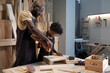 © pressmaster - Portrait of African-American father and son bonding in workshop while building wooden furniture together