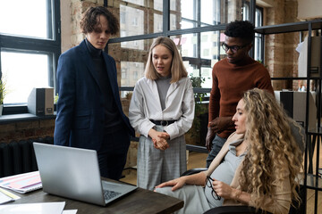 Poster - Pregnant businesswoman discussing online presentation on laptop with her employees during their teamwork at office