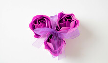 Three Pink Soap Roses Tied With A Lilac Ribbon On A White Background