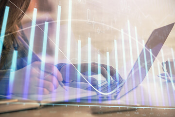  Double exposure of businesswoman hands typing on computer and forex graph hologram drawing. Financial analysis concept.