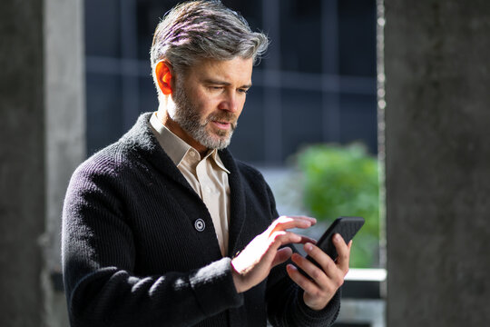 Senior male office worker ordered a taxi or sends an online text message on a mobile phone