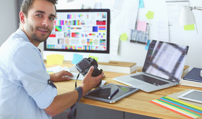 Poster - Portrait of young designer sitting at graphic studio in front of laptop and computer while working online.