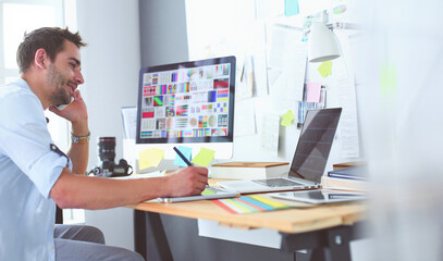 Poster - Portrait of young designer sitting at graphic studio in front of laptop and computer while working online.