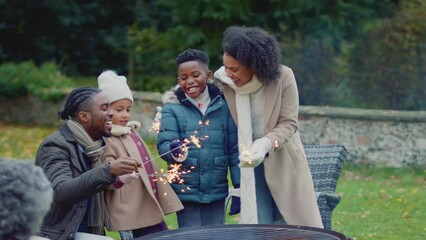 Wall Mural - Family having fun with sparklers in autumn garden at home - shot in slow motion