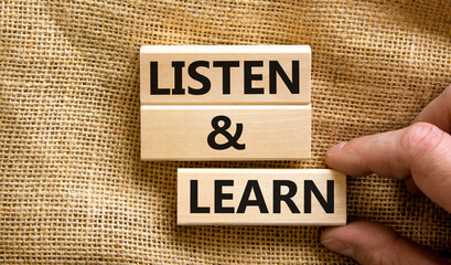 Poster - Listen and learn symbol. Concept words Listen and learn on wooden blocks. Beautiful canvas table canvas background. Businessman hand. Copy space. Business, educational and listen and learn concept.