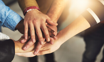 Poster - Were united as a team. Shot of a group of people putting their hands together.