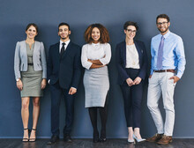 Surrounded By Business Minded Individuals. Studio Shot Of A Group Of Businesspeople Standing In Line Against A Gray Background.