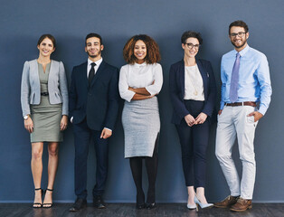 Poster - Surrounded by business minded individuals. Studio shot of a group of businesspeople standing in line against a gray background.