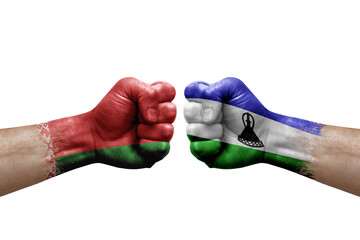 Two hands punch to each others on white background. Country flags painted fists, conflict crisis concept between belarus and lesotho