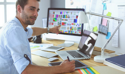 Poster - Portrait of young designer sitting at graphic studio in front of laptop and computer while working online.