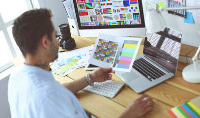 Poster - Portrait of young designer sitting at graphic studio in front of laptop and computer while working online.
