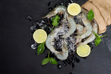 Canvas Print - Fresh shrimp with lemon basil leaves on ice Raw shrimp from the sea placed on a black table, seafood menu, top view.