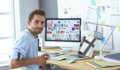 Poster - Portrait of young designer sitting at graphic studio in front of laptop and computer while working online.