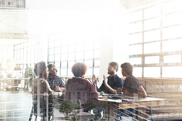 Poster - Collaborating to build the city of their dreams. Multiple exposure shot of businesspeople having a meeting superimposed over a cityscape.