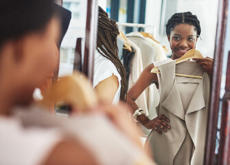 This is just the update my wardrobe needs. Cropped shot of a woman in a store holding a garment in front of herself in the mirror.