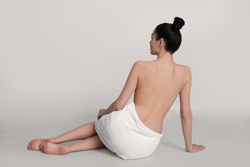 Sticker - Back view of woman with perfect smooth skin sitting on light background