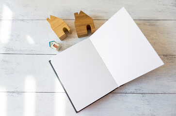 Blank note book with hosue model on white table background, house planing, property investment or house loan, study architecture