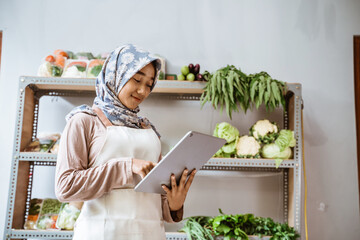 Sticker - Girl in headscarf selling vegetables using a pad