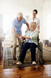 © Anne/peopleimages.com - Surrounded by support. Shot of a smiling caregiver with a senior woman in a wheelchair and her husband at home.