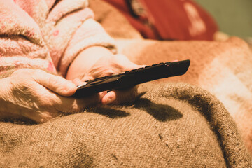 an woman holds in her hand two remotes from the TV at home watching a movie, the remote control is in the hand of the women