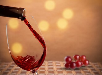 Sticker - Wine is poured into a glass. Red wine and grapes on a vintage background