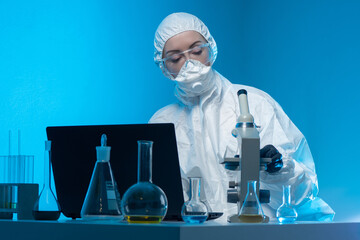 Poster - laboratory technician. woman scientist in chemical protection suit. researcher works with microscope