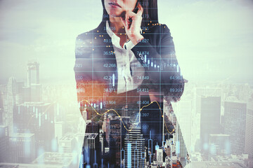 Poster - Attractive thoughtful european businesswoman standing on bright city background with candlestick forex grid chart. Trade, finance and economy concept. Double exposure.