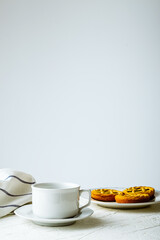 Wall Mural - A vertical shot of a white mug and cookies on a wooden table against a white wall with copy space