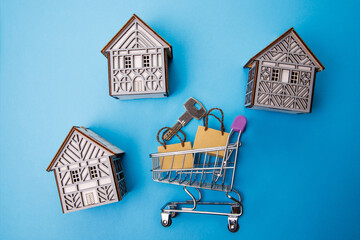 Three houses and a shopping cart. Shopping trolley with packages on a blue background. Business concept of Real Estate. Home Property for Sale. 