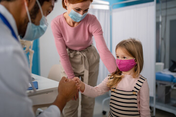 Wall Mural - little girl with her mother at doctor's office on consultation, coronavirus concept.