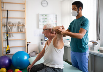 Wall Mural - Young physiotherapist exercising with senior patient in a physic room.