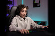 © ABCreative - Surprised school-age gamer with headset boy sits late at night in front of computer monitor playing multiplayer shooter video games with team excitement of virtual world room lit up with led lights
