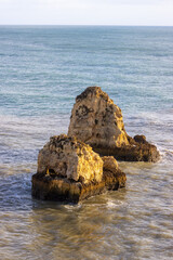 Sticker - A vertical shot of the beautiful cliffs and the sea. Rocha do Leao, Portimao, Portugal.