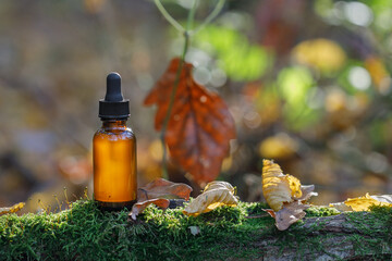 Wall Mural - Brown cosmetic bottles against background of autumn forest, nature. Basis of inspiration in cosmetic products. Cosmetic background for product presentation