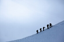 Silhouette Of Group Of Climbers Reaching The Summit