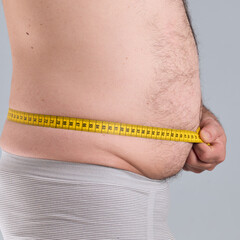 Wall Mural - Man measuring his fat and hairy belly with a tap measure, profile photo, close up look