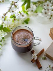 Wall Mural - a hot cup of coffee on the windowsill with branches of blooming white cherry . spring time