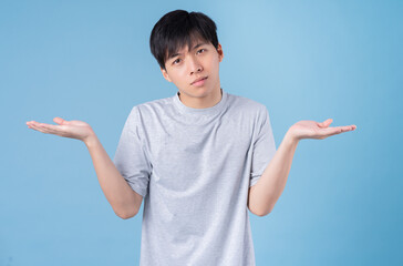 Wall Mural - Young Asian man posing on blue background