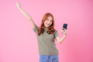 Young Asian woman using smartphone on pink background