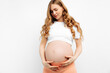 Pregnant happy woman touches her belly. Pregnant mom caressing her belly and smiling close up. Healthy pregnancy concept