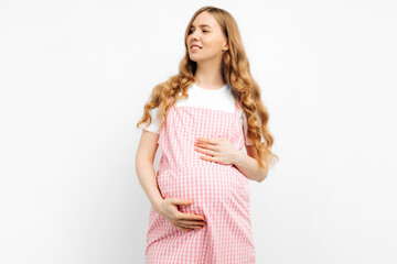 happy pregnant woman in a dress, enjoys her pregnancy, smiles, relaxes, hugs her belly, isolated on white background