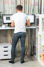 Man Working On Computer At Standing Desk At Home Office